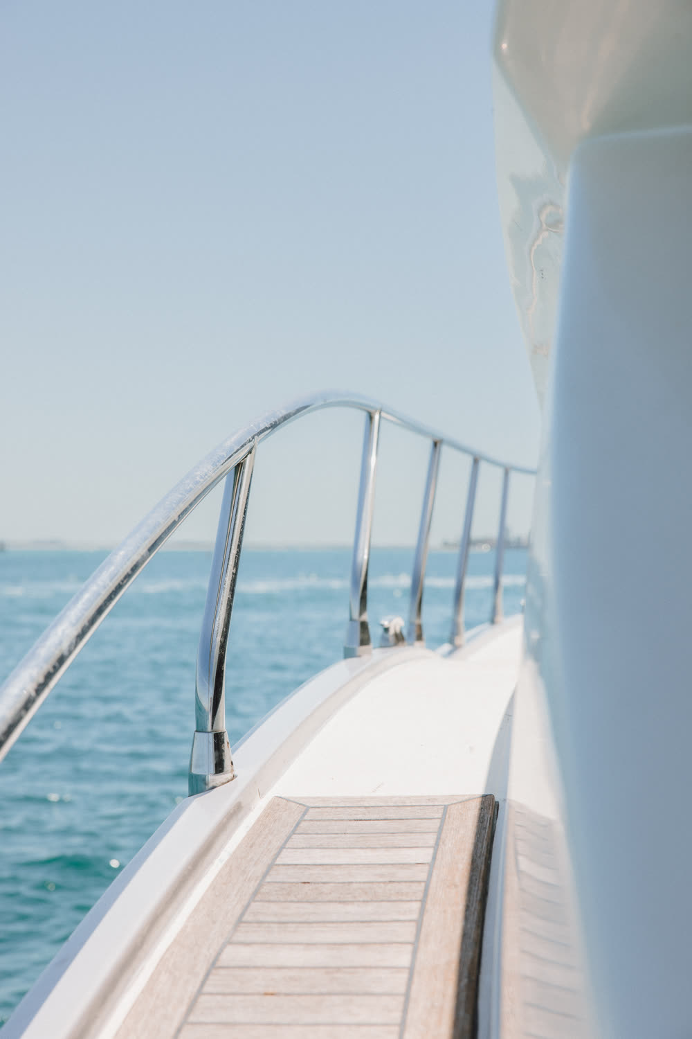 Premium yacht side deck with chrome railing curving toward the Gulf horizon